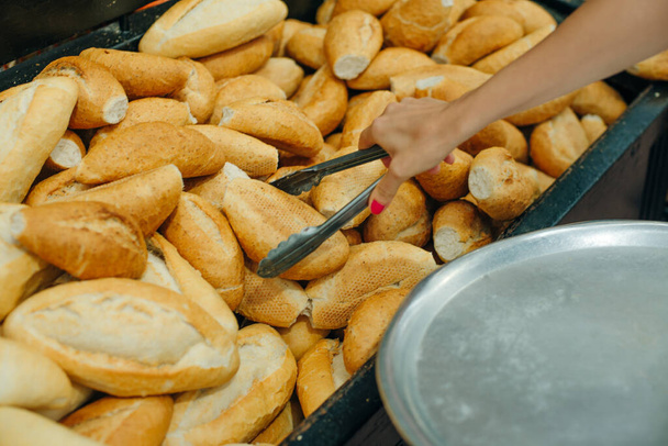 Женщины выбирают хлеб в супермаркете. щипцы и поднос. - Фото, изображение