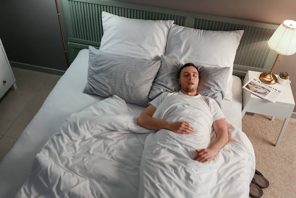 Молодой человек храпит, пока спит в постели. Проблема апноэ
 - Фото, изображение