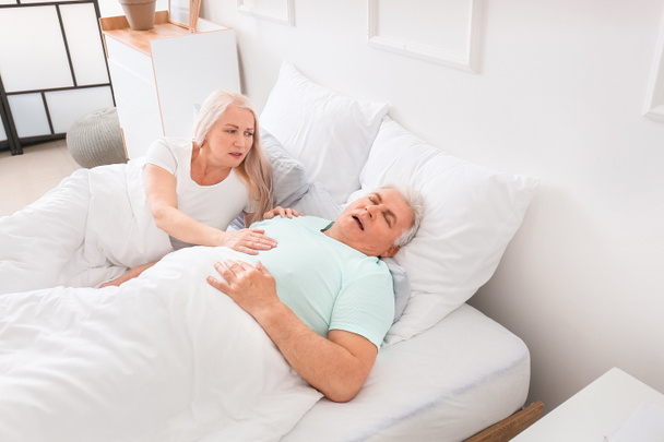 Madura mujer irritada en la cama con ronquidos marido
 - Foto, imagen