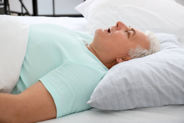 Felnőtt férfi horkol, miközben alszik az ágyban. Apnoe probléma - Fotó, kép