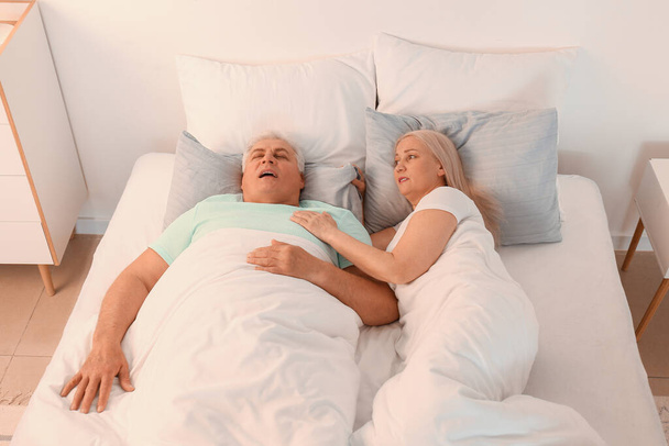 Starší podrážděná žena v posteli s chrápajícím manželem - Fotografie, Obrázek