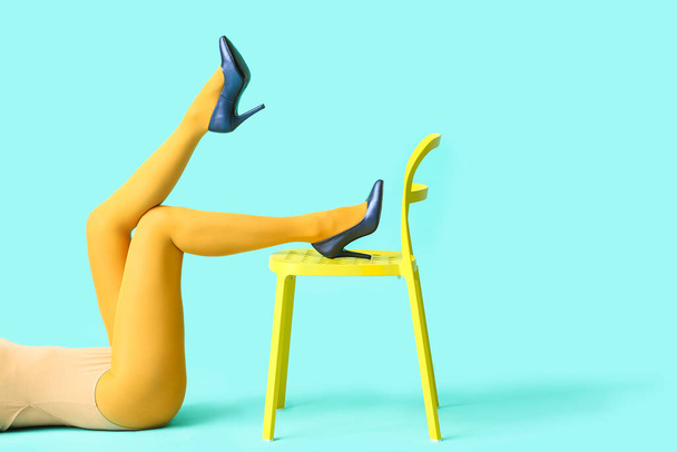 Bella giovane donna in calzamaglia e sedia su sfondo a colori - Foto, immagini