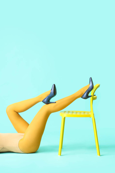 Beautiful young woman in tights and chair on color background - Foto, afbeelding