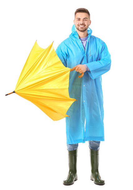 Nuori mies sadetakissa ja sateenvarjo valkoisella pohjalla - Valokuva, kuva