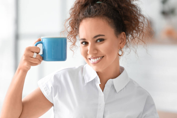美しい若いアフリカ系アメリカ人女性が自宅で熱いお茶を飲む - 写真・画像