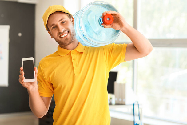 Entrega hombre con botella de agua y teléfono móvil en la oficina
 - Foto, Imagen
