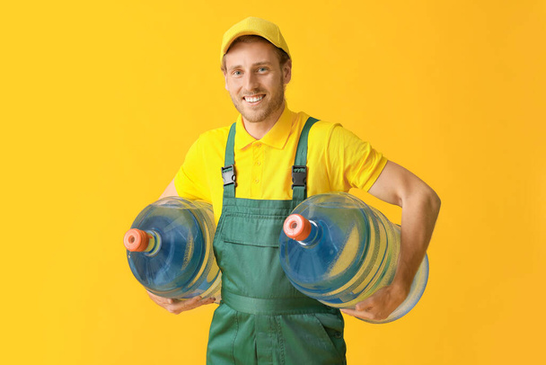 Delivery man with bottles of water on color background - Zdjęcie, obraz