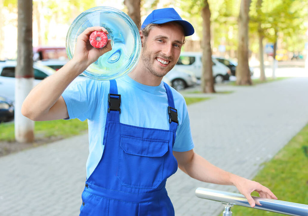 Delivery man with bottle of water outdoors - Foto, Imagen