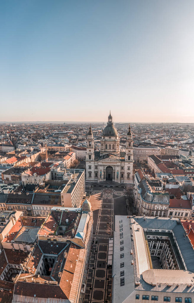 Aerial drone shot of St. Stephen's Basilica with empty square in Budapest sunrise glow in winter - Photo, Image