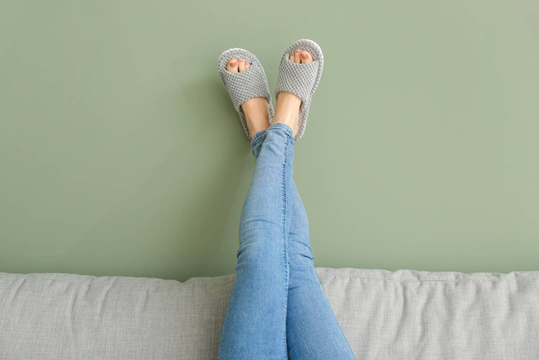 Woman in soft slippers lying on sofa at home - 写真・画像