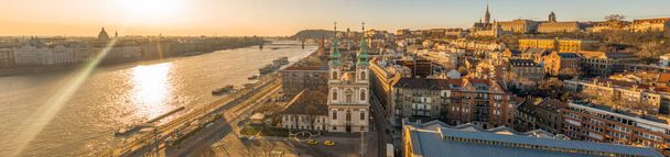 Panorama-Drohnenaufnahme der Pfarrkirche St. Anna in Budapest bei Sonnenaufgang mit Fischerbastei im Hintergrund - Foto, Bild
