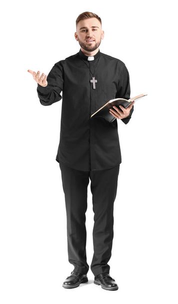 Hermoso joven sacerdote con la Biblia sobre fondo blanco
 - Foto, Imagen