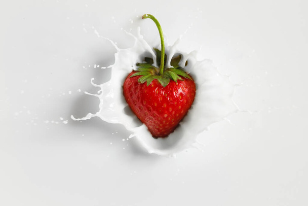Falling of fresh strawberry into milk - Фото, зображення