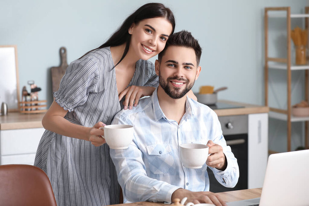 Happy young couple drinking tea at home - Fotó, kép