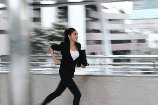 Abstrakte verschwommene Bewegung einer jungen asiatischen Geschäftsfrau, die zur Arbeit rennt. - Foto, Bild