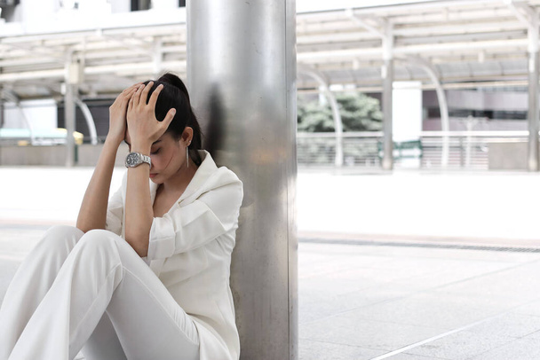 sfrustrowana młoda Azjatka biznes kobieta z rękami na twarzy siedzi na zewnątrz. - Zdjęcie, obraz