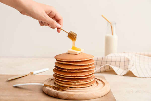 Woman pouring honey onto tasty pancakes - Photo, Image