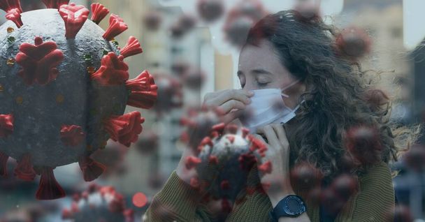 Digital illustration of macro Covid-19 cells floating over a woman wearing a face mask, sneezing. Coronavirus Covid-19 pandemic concept digitally generated - Фото, изображение