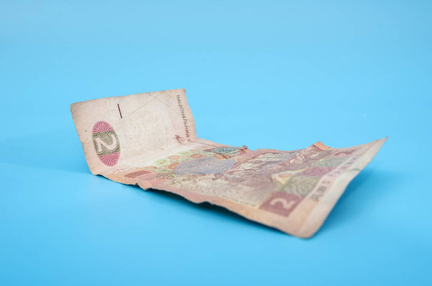 Ukrajinská bankovka s nominální hodnotou dvou hřiven na modrém pozadí. Zmačkaná stará bankovka.Symbol krize a chudoby. - Fotografie, Obrázek