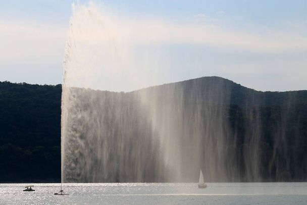 Photos of a beautiful fountain and yacht on the blue lake - Фото, изображение