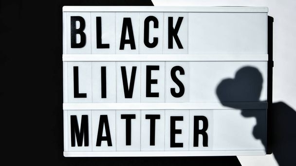 BLACK LIVES MATTER text with deep shadows of heart on a black and white background. Protest against the end of racism, anti-racism, equality. Poster on violation of human rights - Photo, Image