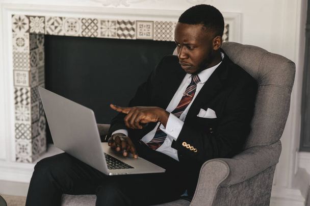 Focused black businessman in suit, holding video call with clients on laptop. Concentrated millennial man in suit giving online conference consulting customer - Foto, Imagen