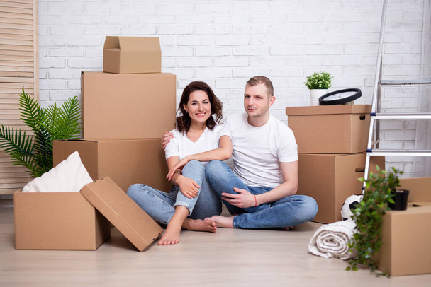 moving day concept - νεαρό ζευγάρι που ξεκουράζεται μετά τη μετακόμιση σε νέο σπίτι ή διαμέρισμα - Φωτογραφία, εικόνα