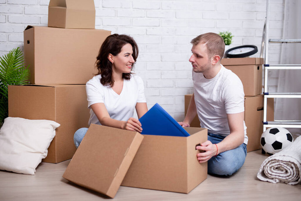 feliz pareja joven embalaje cajas de cartón para mover en casa nueva
 - Foto, Imagen