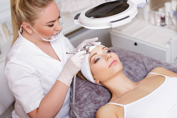 retrato del cosmetólogo hermoso haciendo procedimiento de oxígeno facial para la mujer joven en el salón de belleza moderno
 - Foto, Imagen