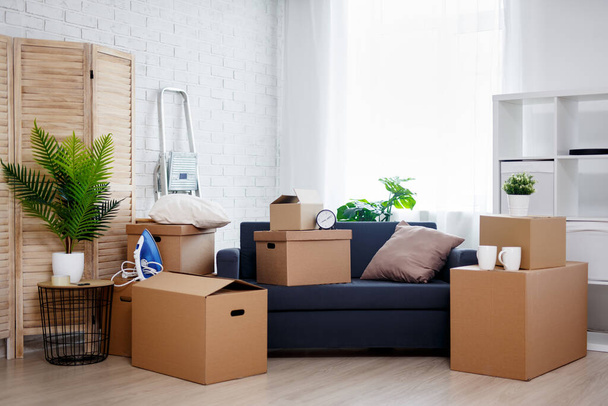 moving day concept - στοίβα από κουτιά από χαρτόνι με αντικείμενα σε νέο σπίτι - Φωτογραφία, εικόνα