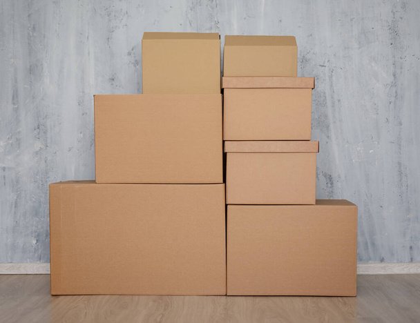 día móvil o concepto de entrega postal - pila de cajas de cartón marrón sobre fondo de pared gris
 - Foto, imagen
