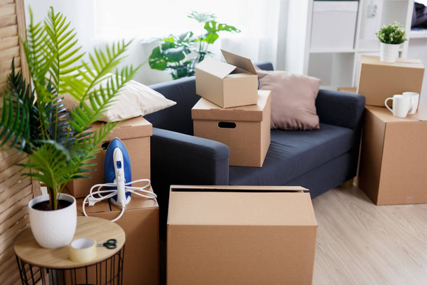 Концепция дня переезда - стопка коробок из коричневого картона с вещами в новом доме
 - Фото, изображение