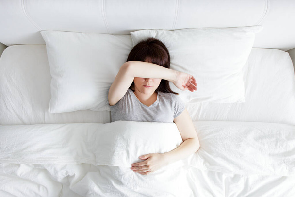 stressz és álmatlanság koncepció - felső nézet a fiatal nő fekszik az ágyban, és fedezze arcát kézzel - Fotó, kép