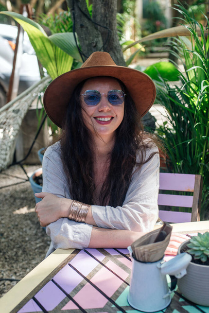 Привлекательная девушка-туристка в солнечных очках, блузка и шляпа в уличном кафе. Концепция туризма, путешествий, отдыха - Фото, изображение