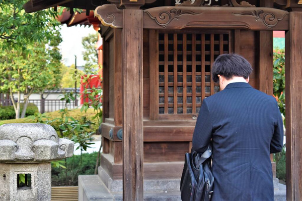 青いスーツのアジアの男が神社で祈りの弓 - 写真・画像