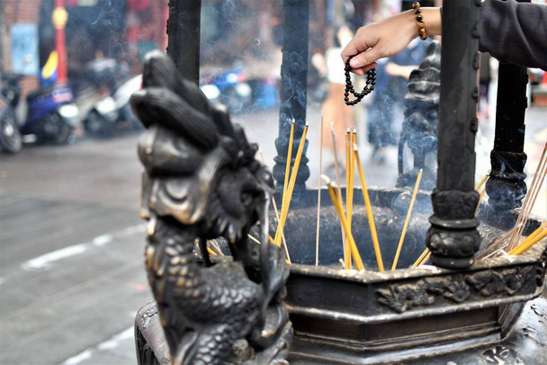 Un adoratore usa perline per pregare come bastoncini di incenso bruciati in un tempio cinese - Foto, immagini