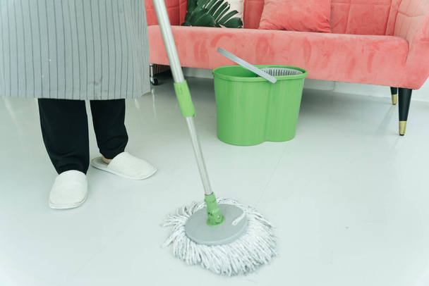 Sprzątanie podłogi z mopem w salonie. Covid-19 Zapobieganie koronawirusom. - Zdjęcie, obraz