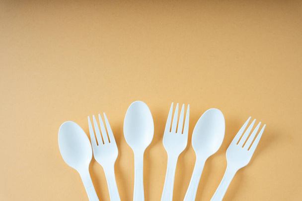 Group of plastic spoon and fork over orange background. Copy space. - Zdjęcie, obraz