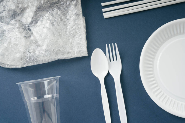 Одноразові пластикові відходи посуду на темно-синьому фоні
. - Фото, зображення