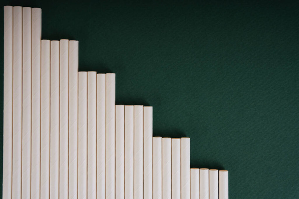 Top view - White straw over dark green background. Copy space. - 写真・画像