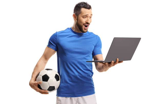 Excited soccer player holding a ball and a looking at a laptop computer isolated on white background - Foto, immagini