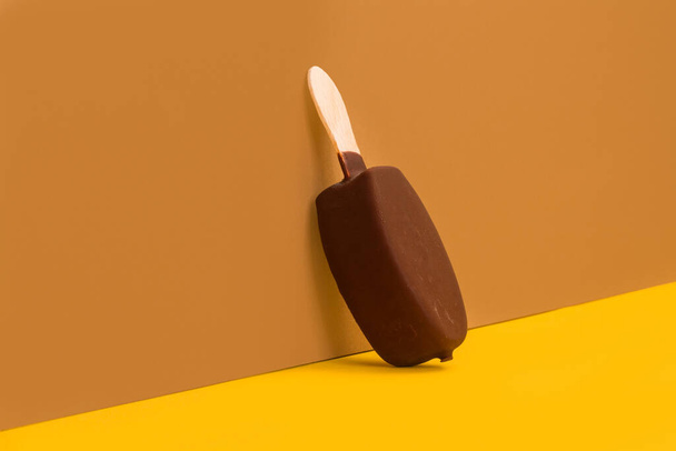 Glace trempée au chocolat sur fond brun et jaune - Photo, image