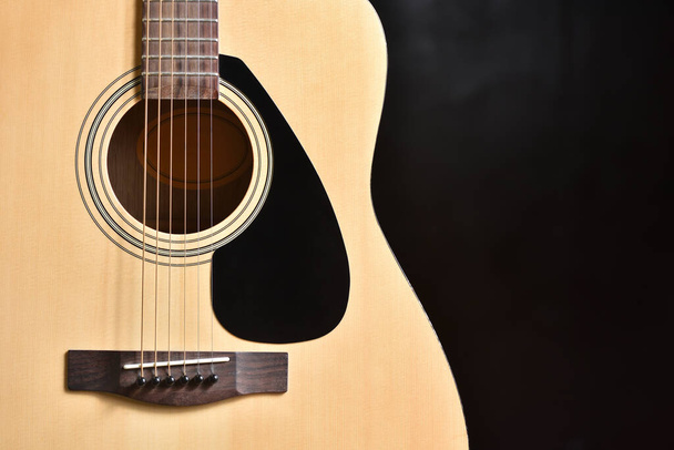 Acoustic guitar and its round hole socket closeup against a dark background and copy space - Photo, Image