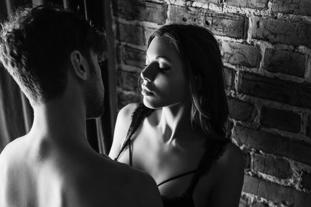 Yksivärinen kuva seksikäs nainen rintaliivit seisoo lähellä paidaton mies ja tiili seinään - Valokuva, kuva