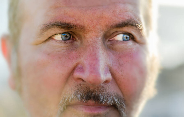 Ritratto di un uomo dagli occhi azzurri che guarda lateralmente la luce - Foto, immagini