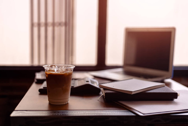 Ice coffee on office workplace with laptop, calculator, book and document on wood table - Foto, Imagem