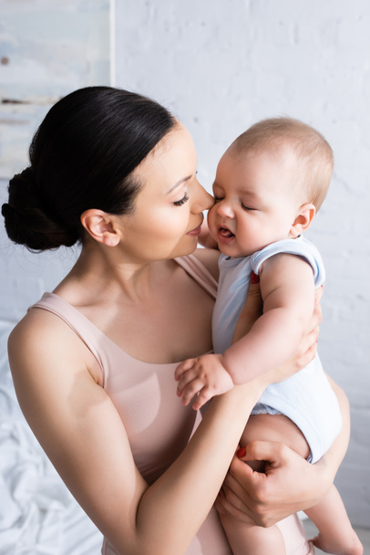 atraktivní matka při pohledu na nemluvně syn v baby rmper  - Fotografie, Obrázek