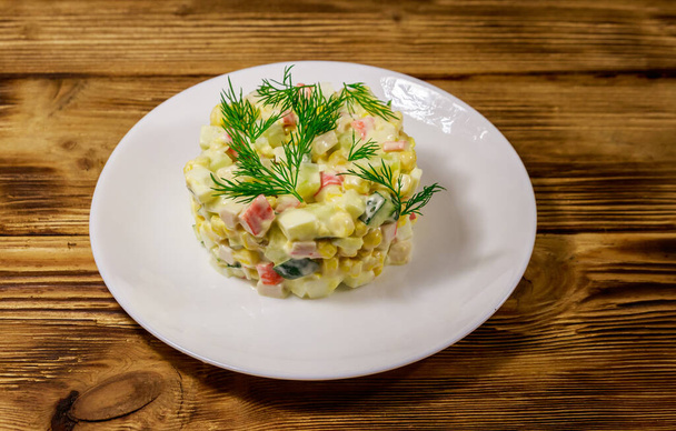 Salade met krab, suikermaïs, komkommer, eieren en mayonaise op houten tafel - Foto, afbeelding