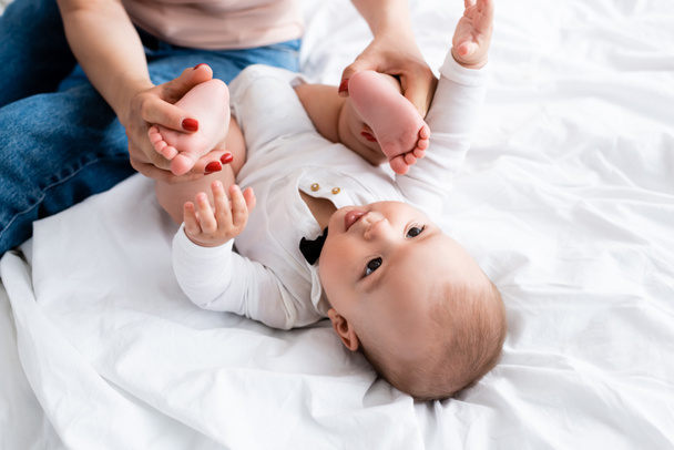 Äiti koskettaa paljain jaloin söpö pikkulapsi poika vauva romper  - Valokuva, kuva