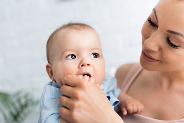 mother looking at cute baby boy sucking hand  - Photo, Image